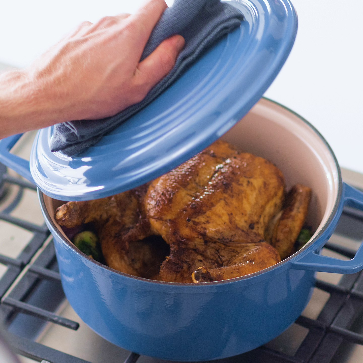 Whole roasted chicken in blue enameled cast iron Dutch oven on stovetop
